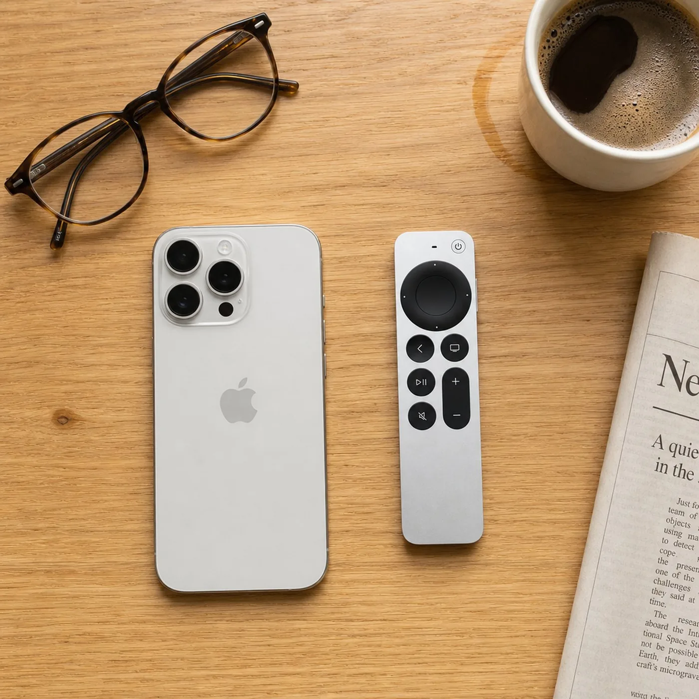 Salontafel met een iPhone, de Siri Remote, een leesbril en een kop koffie