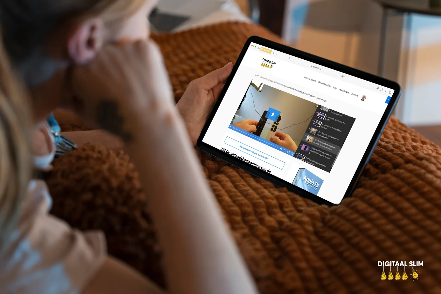 Een vrouw volgt een les uit de Apple TV-cursus op haar iPad, gezellig op de sofa
